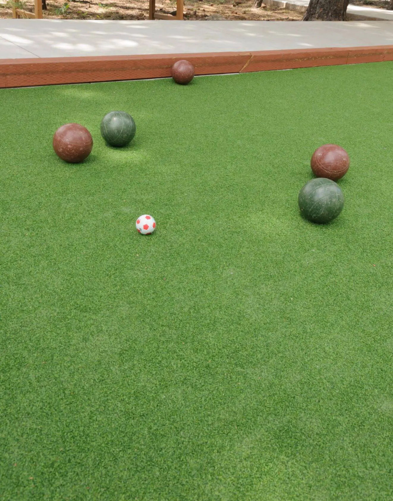 A house with white walls and dark brown roof tiles, surrounded by green plants and flowers. In the foreground, a neatly manicured green lawn showcases the work of Scottsdale Turf Pros. A white truck, likely for turf installation, is partially visible to the right of the house.